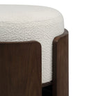 Close-up of the Rondo stool highlighting the modern dark wood frame wrapping seamlessly around the thick white textured bouclé cushion.