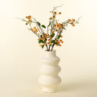 White vase with decorative branches on a beige background