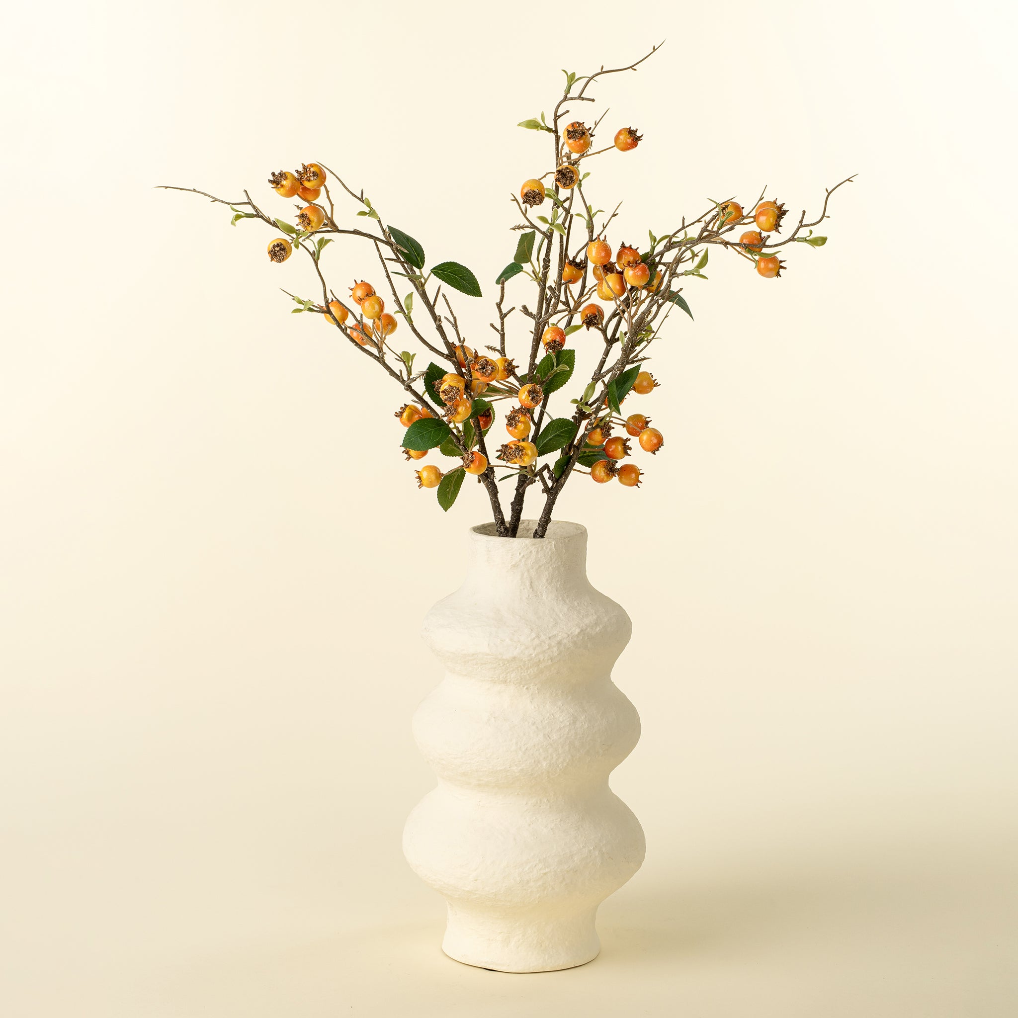 White vase with decorative branches on a beige background