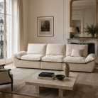 The beige sailing-shaped sofa styled in an elegant Parisian living room with a marble coffee table and gold mirror.