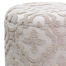 Textured beige ottoman with intricate pattern on a white background