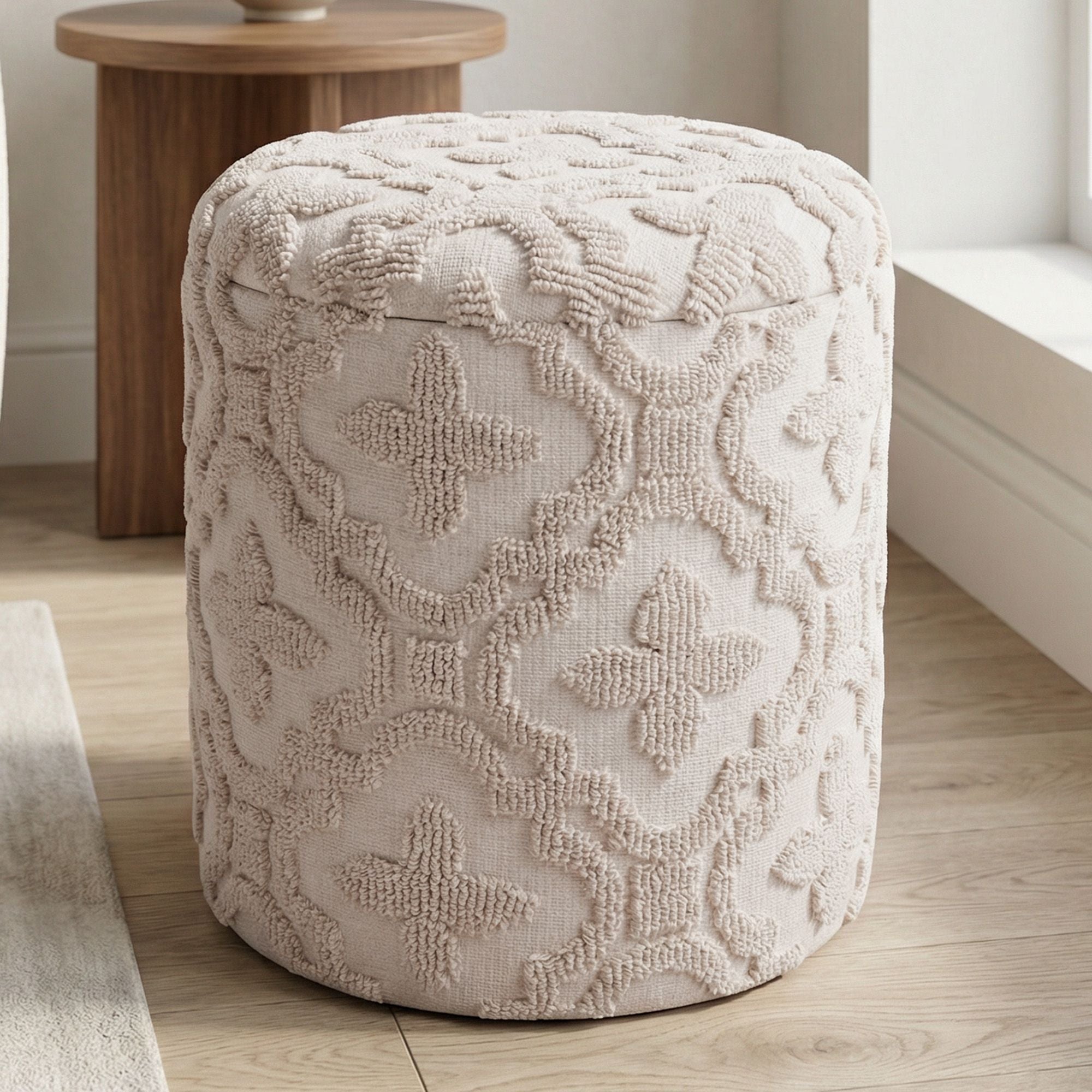 Textured beige ottoman on a wooden floor with a wooden table in the background