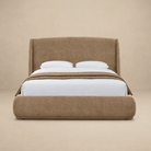 Front view of the Serelle Upholstered Bed in dark beige with a high wingback headboard and rounded frame against a warm beige studio background.