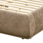 Close-up of the Serelle Upholstered Bed's rounded dark beige frame corner, stitching, wooden slats, and short support foot.