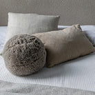 The Serenity natural cushion trio styled on a bed with a bouclé headboard and textured knit throw for a layered look.