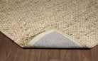 Folded corner of the beige Silas wool rug, revealing its chunky looped surface and sturdy backing