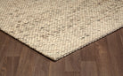 Corner view of the beige and cream Silas hand-woven wool rug laying flat on a hardwood floor