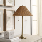 Solara Rattan Glow Table Lamp with woven rattan shade on wooden table beside framed wall art and decor books