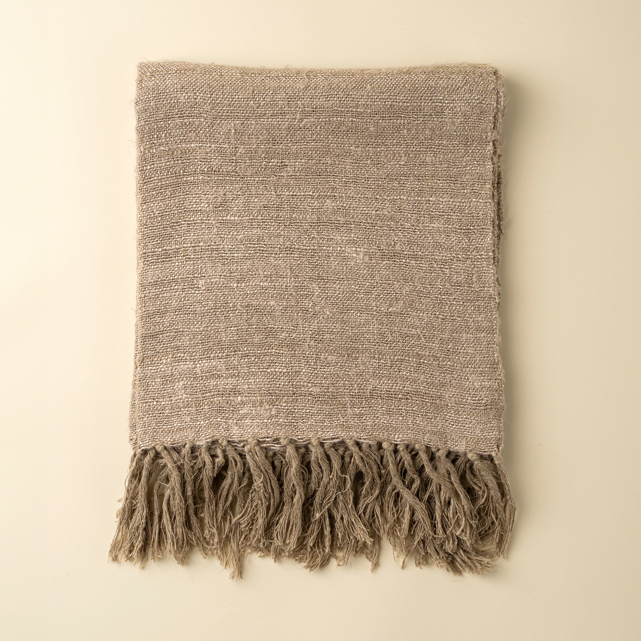 Textured blanket with fringes on a beige background