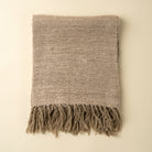 Textured blanket with fringes on a beige background