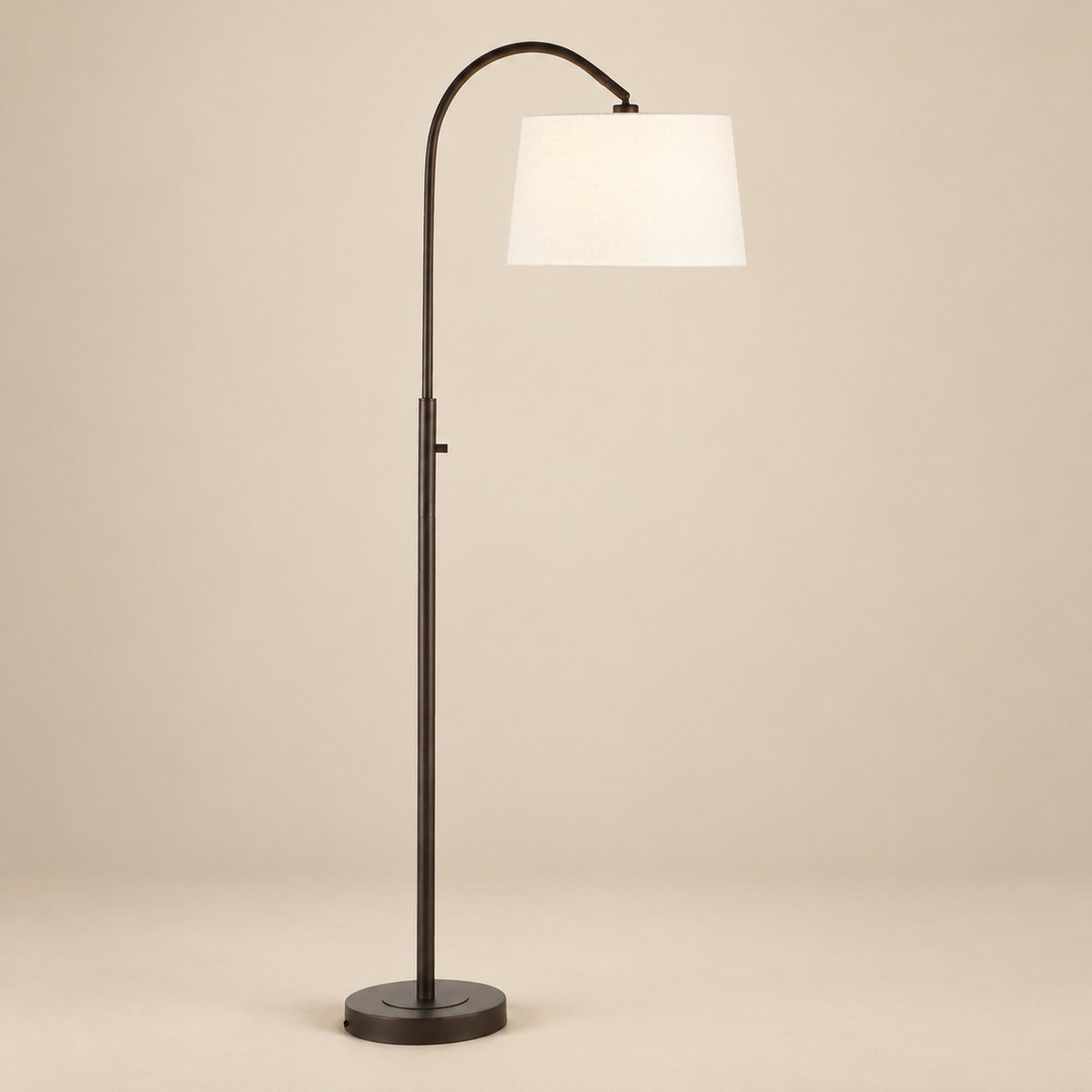 Solenne Arc Floor Lamp in painted bronze with an off-white linen shade on a seamless beige studio background.