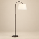 Solenne Arc Floor Lamp in painted bronze with an off-white linen shade on a seamless beige studio background.