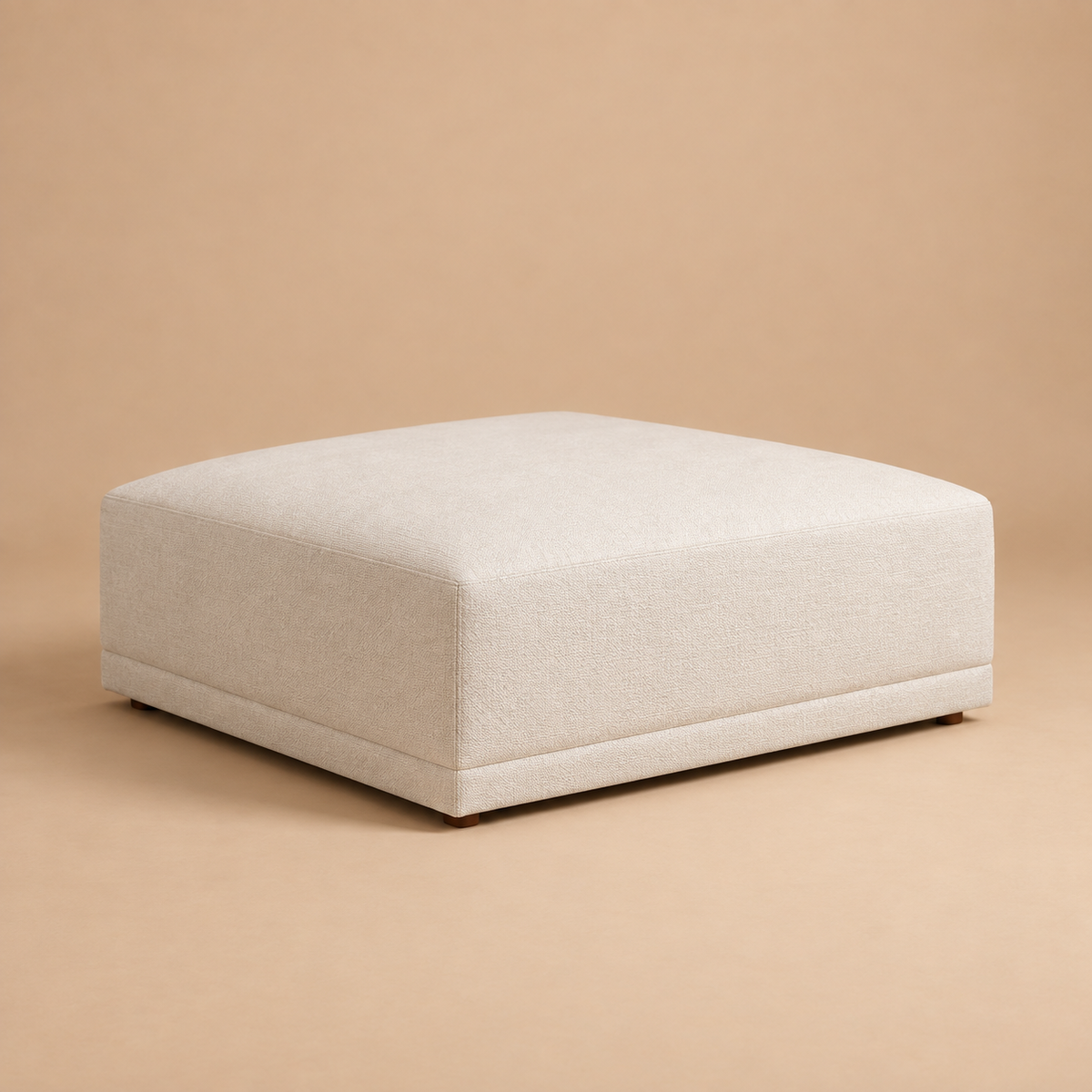Beige Solis ottoman shown from a three-quarter angle against a solid warm studio background.