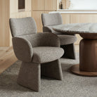 Two charcoal upholstered chairs and a round wooden table in a room with wooden flooring and cabinets featuring the Soren Bouclé Dining Chair
