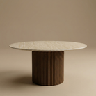 Round dining table with a marble top and ribbed brown base on a beige background