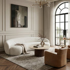 Modern living room with a white sofa, brown armchair, and round coffee table.