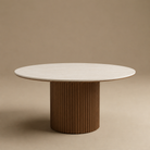 Soren coffee table with a light beige stone top and a fluted brown pedestal base, set against a solid warm beige background.