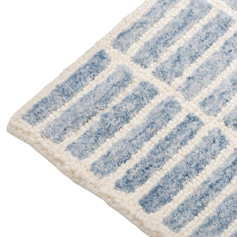 Close-up of the Tessera Hand-Tufted Wool Grid Rug in blue showing the rounded corner and ivory grid pattern.