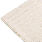 Close-up of the Tessera Hand-Tufted Wool Grid Rug in ivory showing the rounded corner and tonal grid pattern.