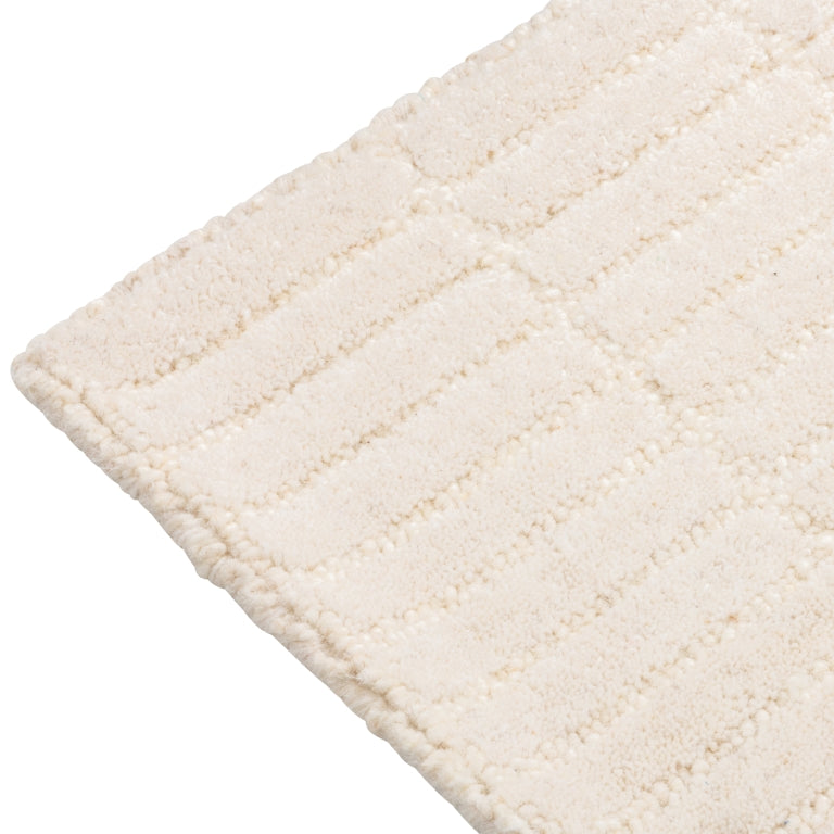 Close-up of the Tessera Hand-Tufted Wool Grid Rug in ivory showing the rounded corner and tonal grid pattern.