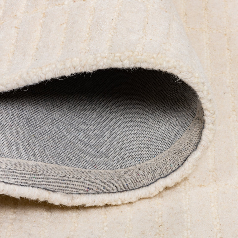 Folded Tessera Hand-Tufted Wool Grid Rug in ivory showing the wool pile, bound edge, and cotton backing.
