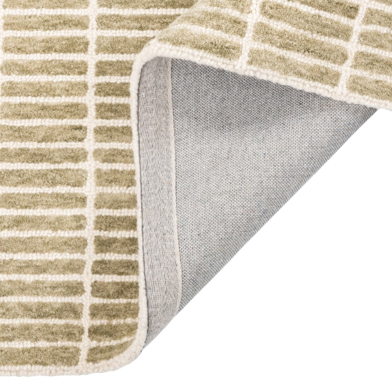 Tessera Hand-Tufted Wool Grid Rug in sage folded back to show its cotton backing and finished edge.