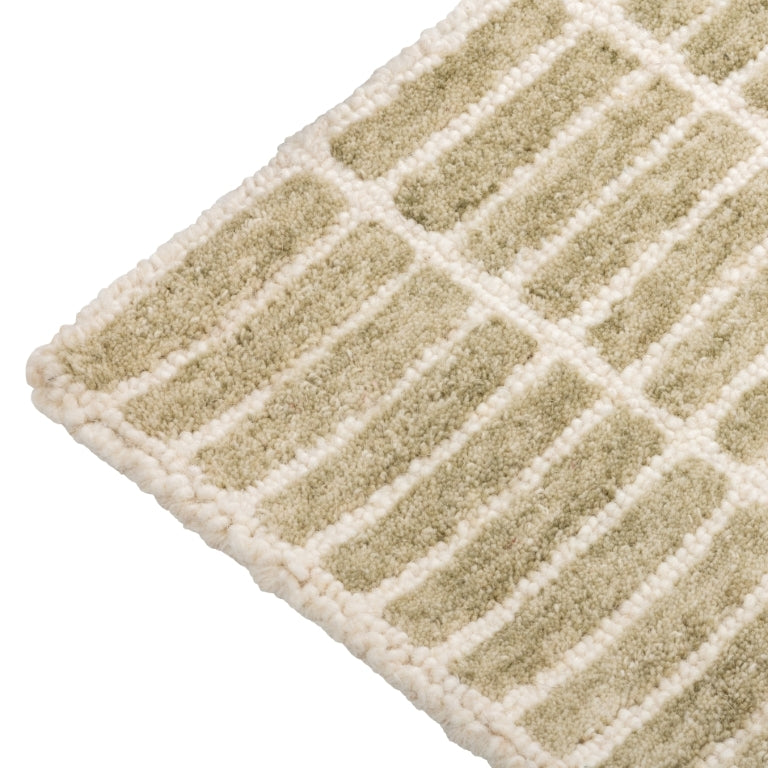 Close-up of the Tessera Hand-Tufted Wool Grid Rug in sage showing the rounded corner and ivory grid pattern.