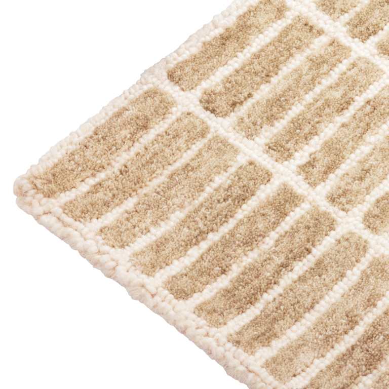 Close-up of the Tessera Hand-Tufted Wool Grid Rug in sand showing the warm beige wool pile and ivory grid pattern.