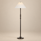 Thalia Dark Bronze Floor Lamp with a sculpted iron stem and off-white linen shade on a seamless beige studio background.