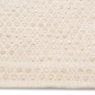 Macro detail of the Theo hand-woven rug surface highlighting the raised, chunky honeycomb texture in ivory cream wool.