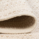 Folded edge view of the ivory Theo wool rug, demonstrating the thick woven pile and reversible hand-woven construction without canvas backing