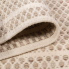 Folded edge view of the husk Theo wool rug, showing the plush thickness of the chunky woven design and the raw hand-woven underside.