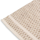 Close-up corner detail of the husk Theo wool rug showing the sturdy edge binding and the contrasting natural yarn colors.