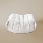 Side view of the White TOGO ottoman on a beige background