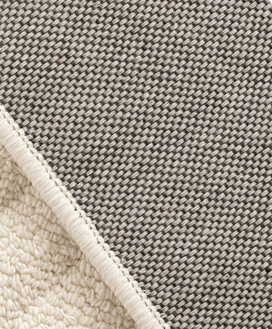 Folded corner of the Tranquil Ivory Carpet showing the cream pile and dark woven backing