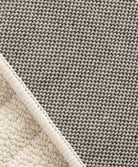 Folded corner of the Tranquil Ivory Carpet showing the cream pile and dark woven backing