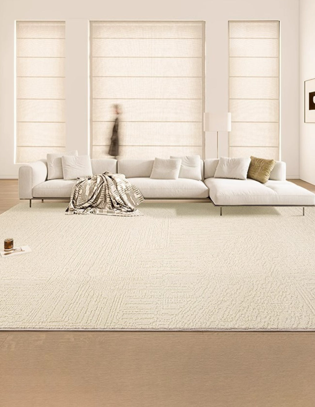 A large, plush, creamy beige area rug in a bright living room setting, complementing the neutral color scheme.