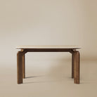 Front view of Valencia dining table with sintered stone top and curved solid wood legs on beige studio background