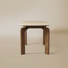 Side view of Valencia dining table with sintered stone top and curved solid wood legs on beige studio background