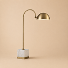 Gold table lamp with marble base on a beige background