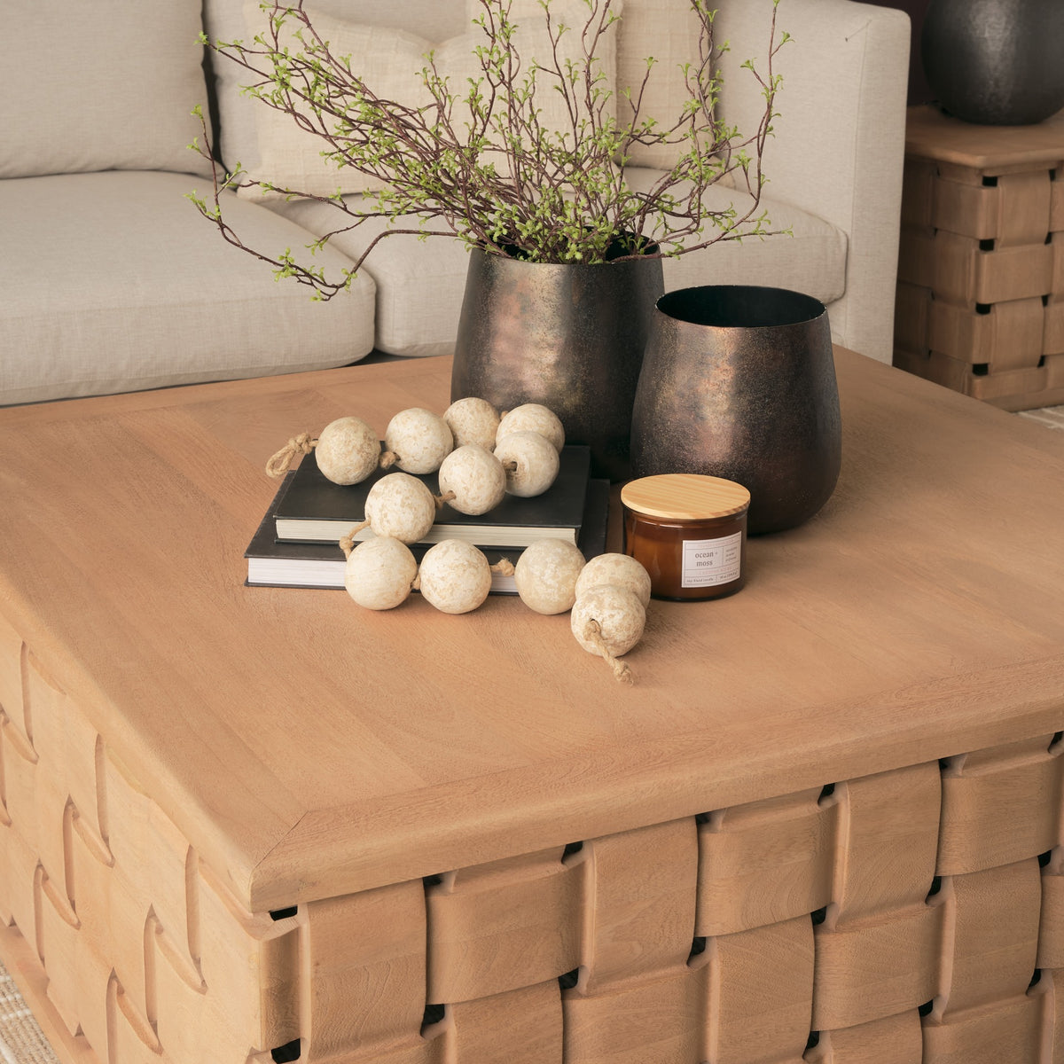 Lifestyle detail of the Varelle Square Coffee Table showing the solid mango wood top styled with books, vases and a candle.