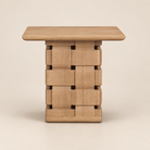 Front studio view of the Varelle Carved Mango Wood Square Side Table with a light brown mango wood top and carved woven pedestal base on a warm beige background.