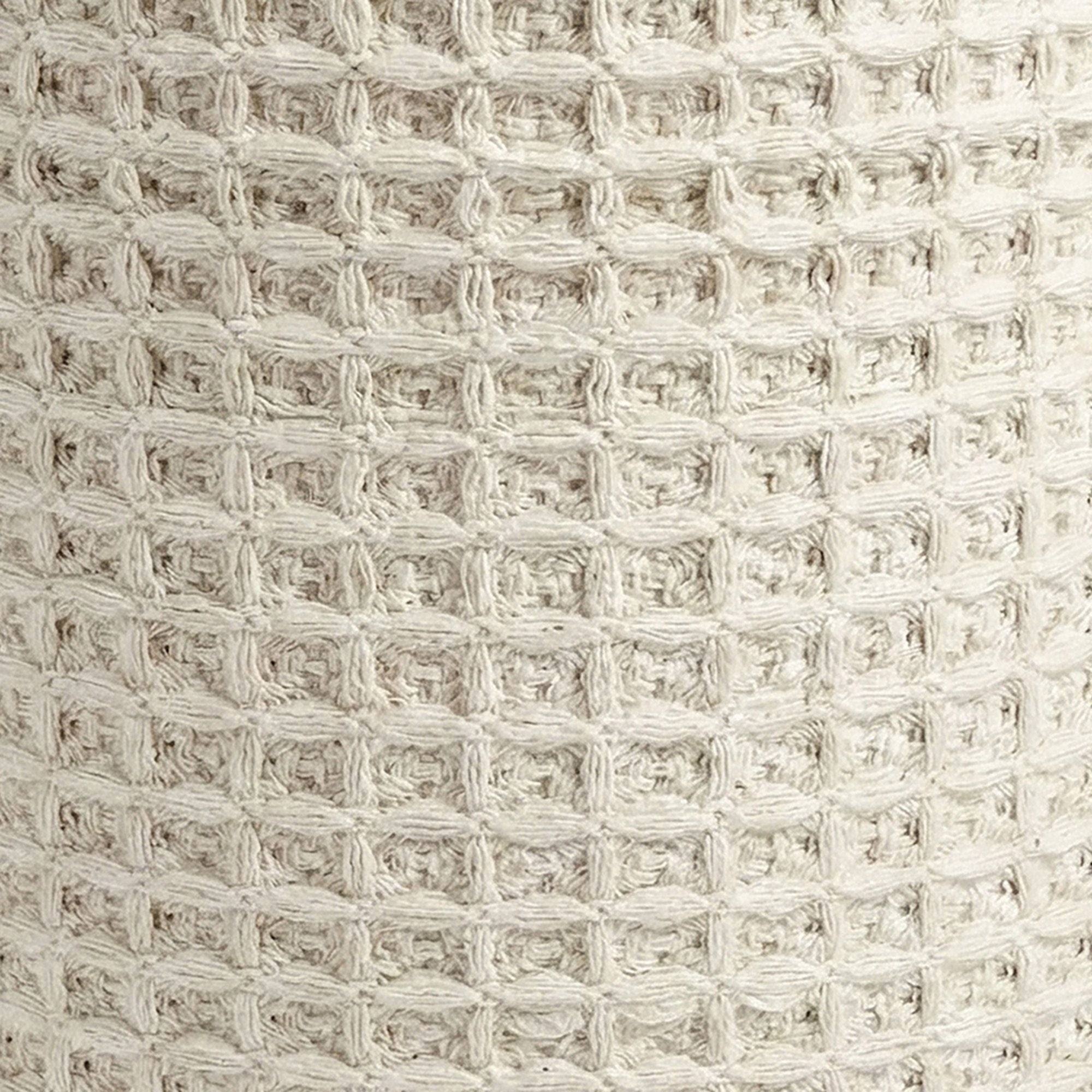 Close-up of a textured beige fabric with a grid pattern