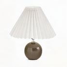 Vela Ceramic Table Lamp with a glossy dark brown rounded base and white pleated shade.