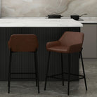 Two brown bar stools in a kitchen setting with a marble backsplash.