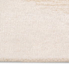 Macro detail of the vinne rug's surface, highlighting the soft ivory wool texture and the raised tufting of the diamond pattern.