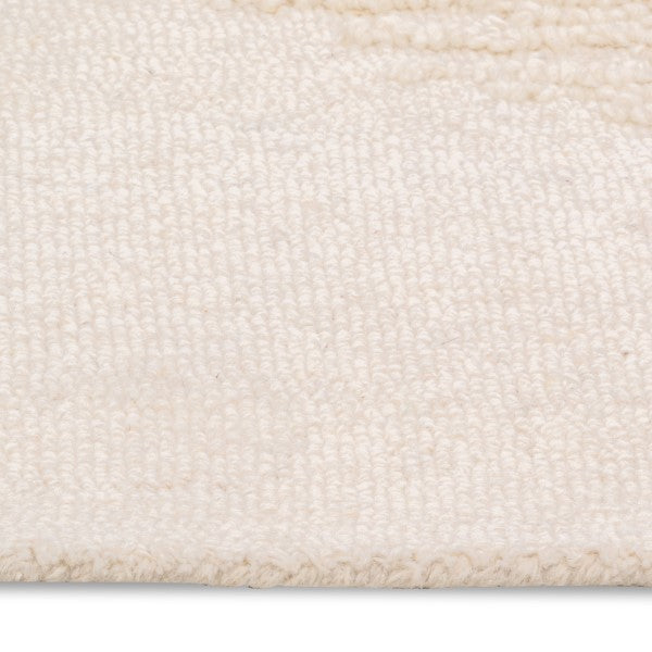 Macro detail of the vinne rug's surface, highlighting the soft ivory wool texture and the raised tufting of the diamond pattern.