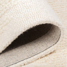 Folded corner of the Vinne wool rug revealing the durable grey canvas backing typical of high-quality hand-tufted construction