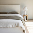 Front view of the Vivienne bed styled with a pleated table lamp and textured linen pillows in a bright, airy room.