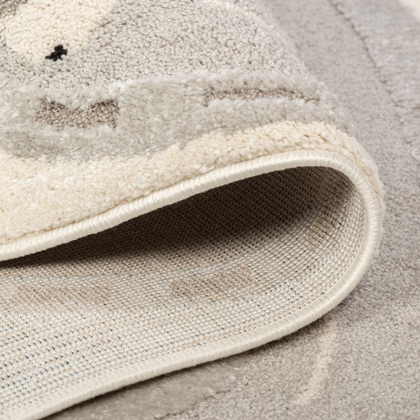 Folded detail of the Zoomie Lane Kids Rug showing the bound edge and woven backing.